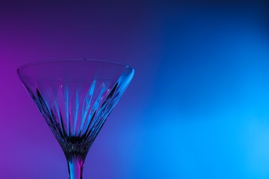 Empty clean martini glass in neon lights, space for text