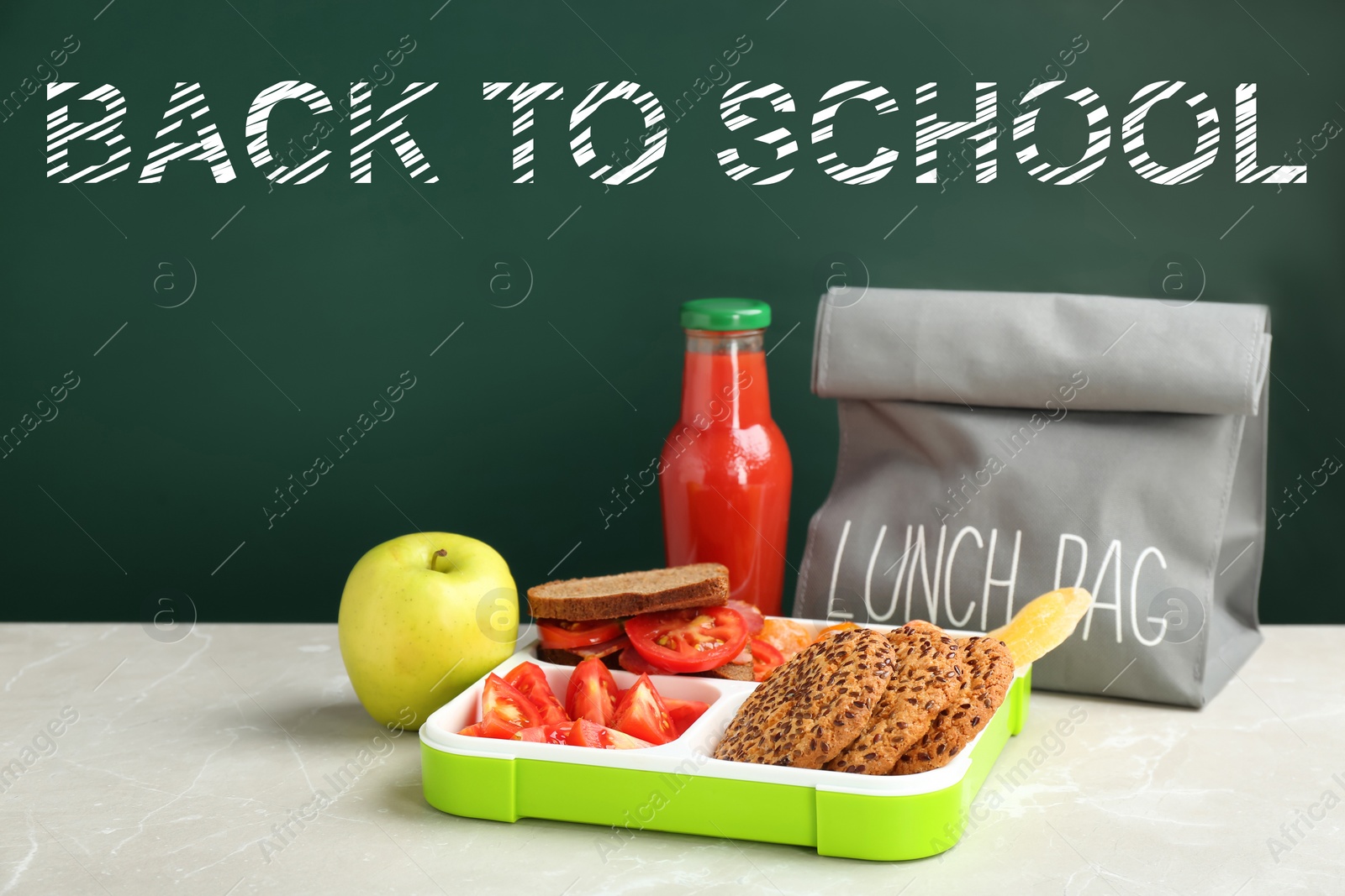 Image of Lunch box with appetizing food and bag on table near chalkboard