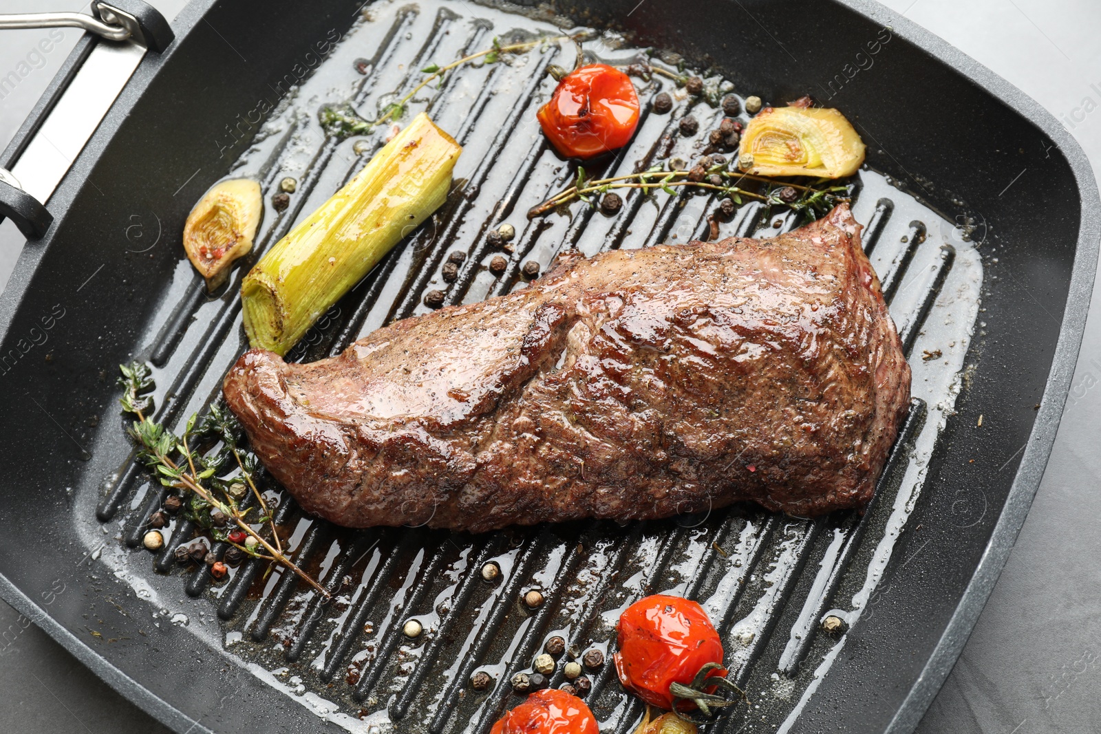 Photo of Delicious grilled beef meat and vegetables in pan on grey table, top view