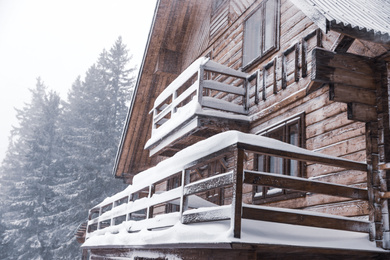 Modern wooden cottage on snowy day. Winter vacation