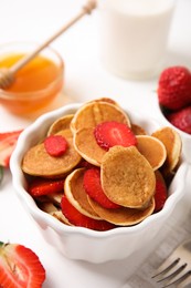 Photo of Delicious mini pancakes cereal with strawberries served on table