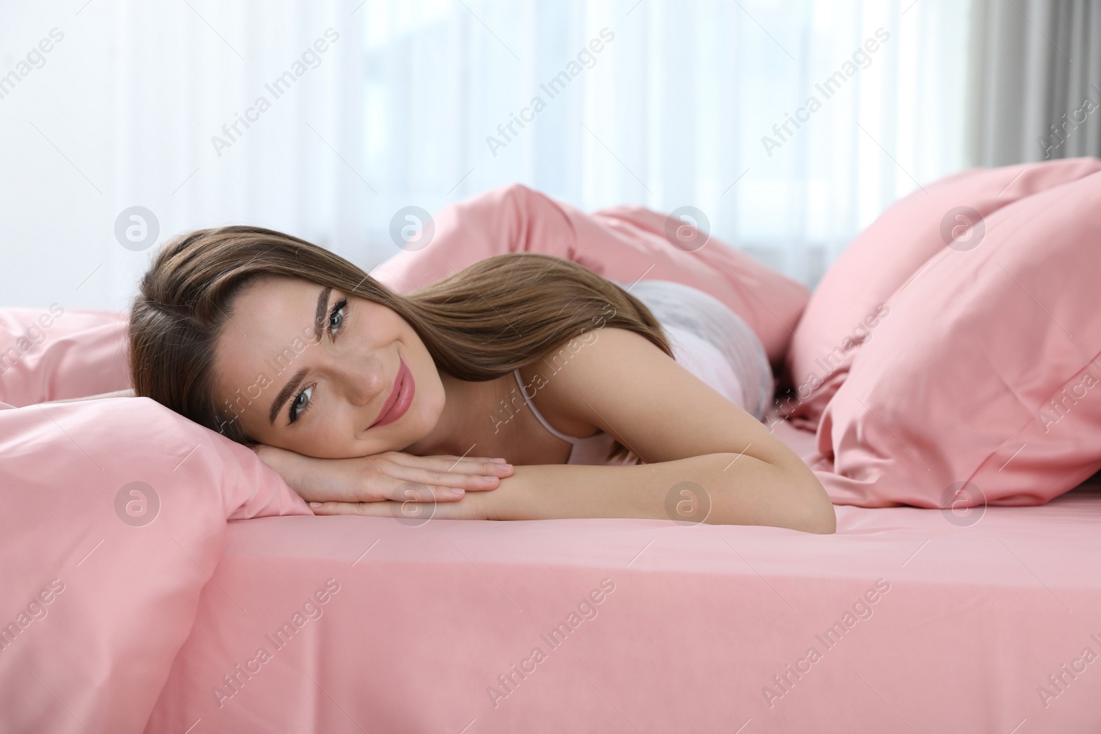 Photo of Young woman lying on comfortable bed with silky linens