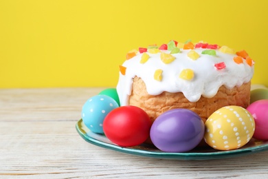 Photo of Easter cake and colorful eggs on white wooden table