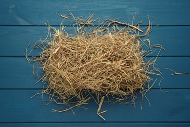 Photo of Heap of dried hay on blue wooden background, flat lay