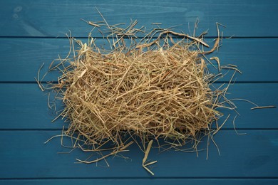 Heap of dried hay on blue wooden background, flat lay