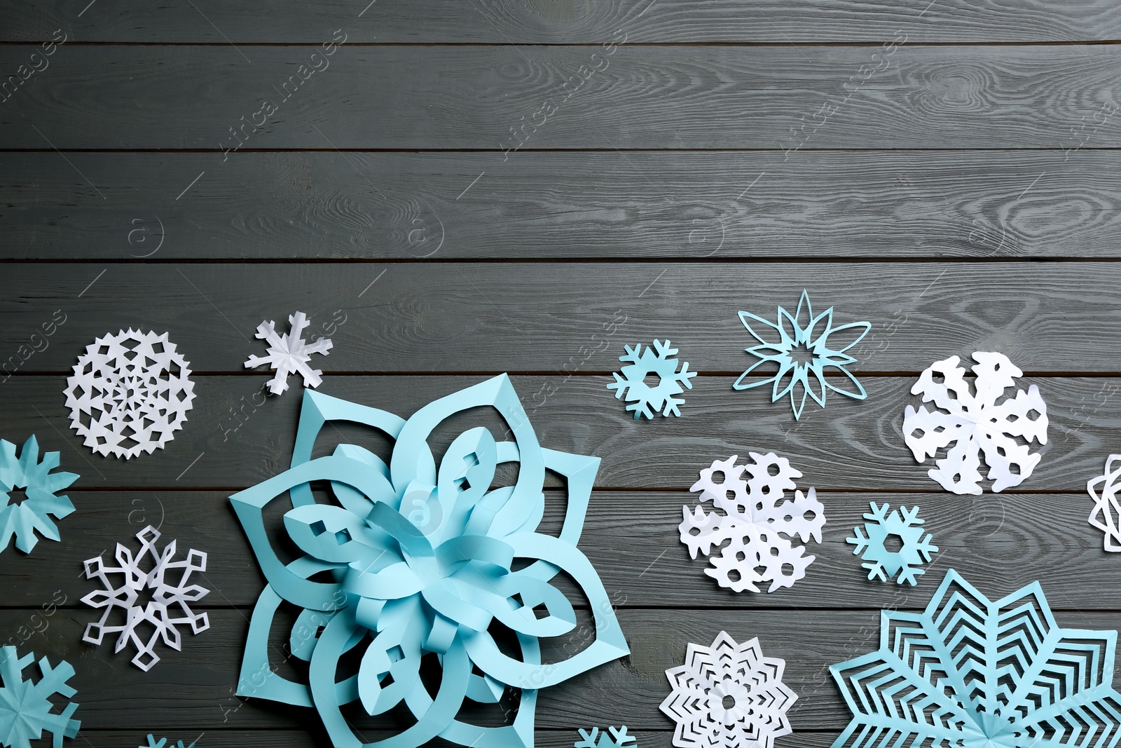 Photo of Many paper snowflakes on grey wooden background, flat lay. Space for text