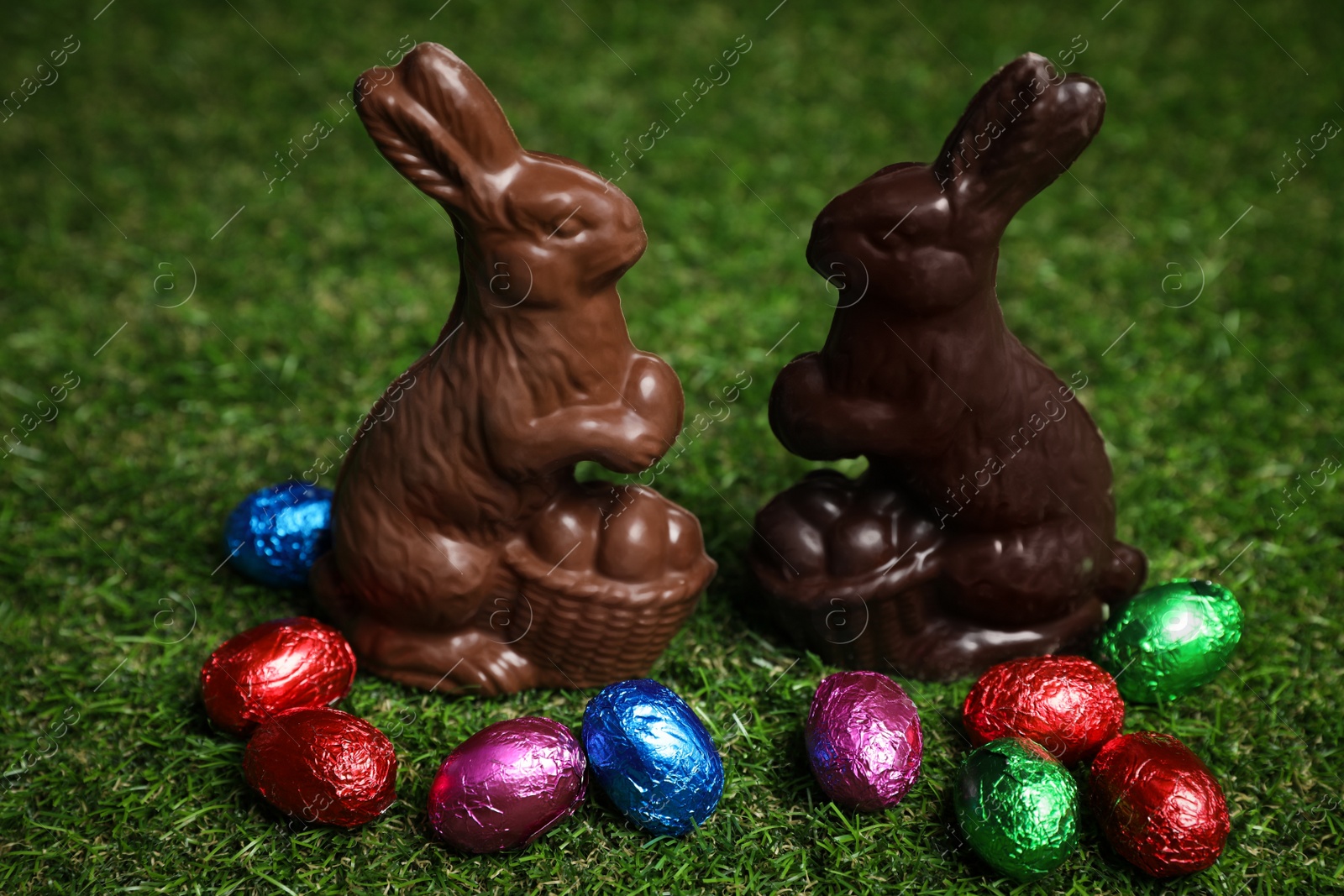 Photo of Chocolate bunnies and eggs on green grass. Easter celebration