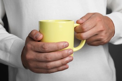 Photo of Man holding yellow mug on grey background, closeup