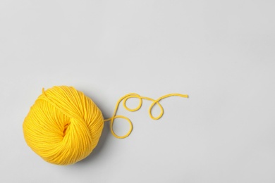 Photo of Soft yellow woolen yarn on white background, top view. Space for text