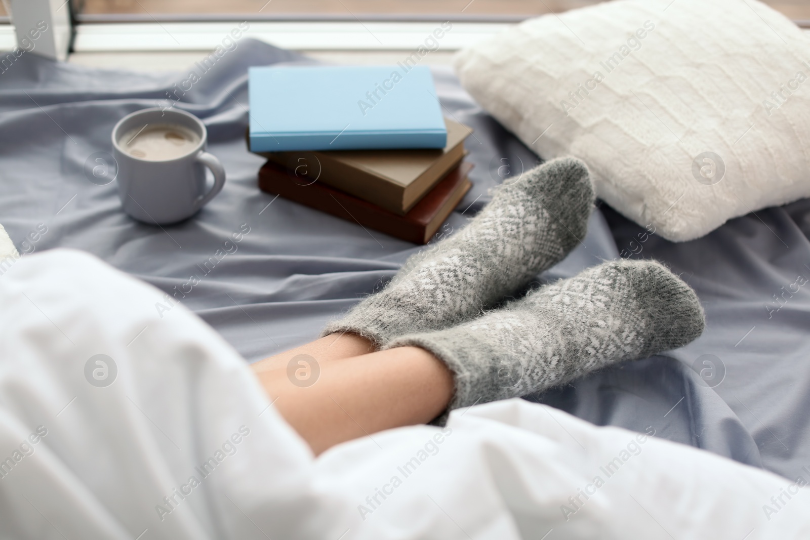 Photo of Young woman lying on bed, closeup view of legs. Winter atmosphere