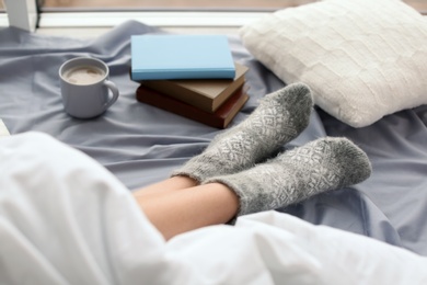 Photo of Young woman lying on bed, closeup view of legs. Winter atmosphere