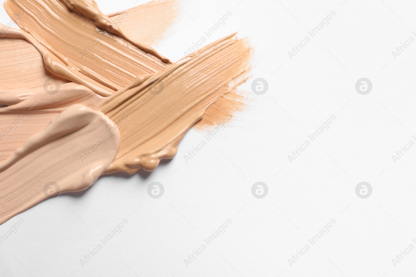 Photo of Samples of skin foundation on white background, closeup. Space for text