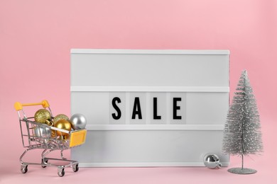 Photo of Lightbox with word Sale and Christmas decor on pink background
