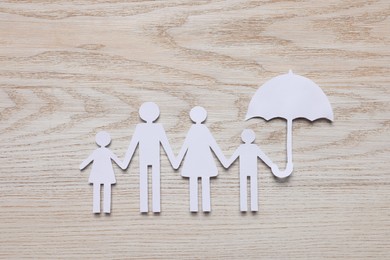 Photo of Paper family cutout on white wooden background, top view. Insurance concept