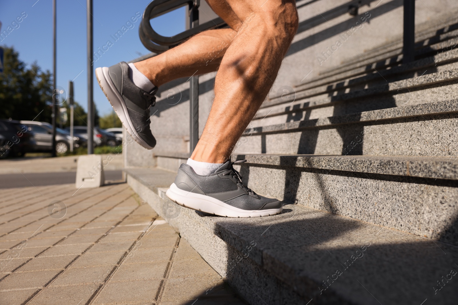 Photo of Man running up stairs outdoors on sunny day, closeup