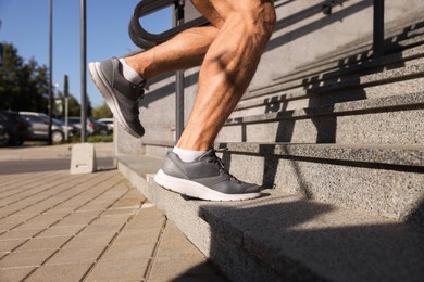 Photo of Man running up stairs outdoors on sunny day, closeup