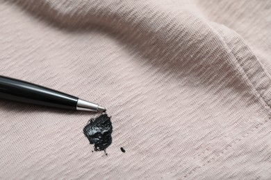 Photo of Pen and stain of black ink on beige shirt, closeup. Space for text