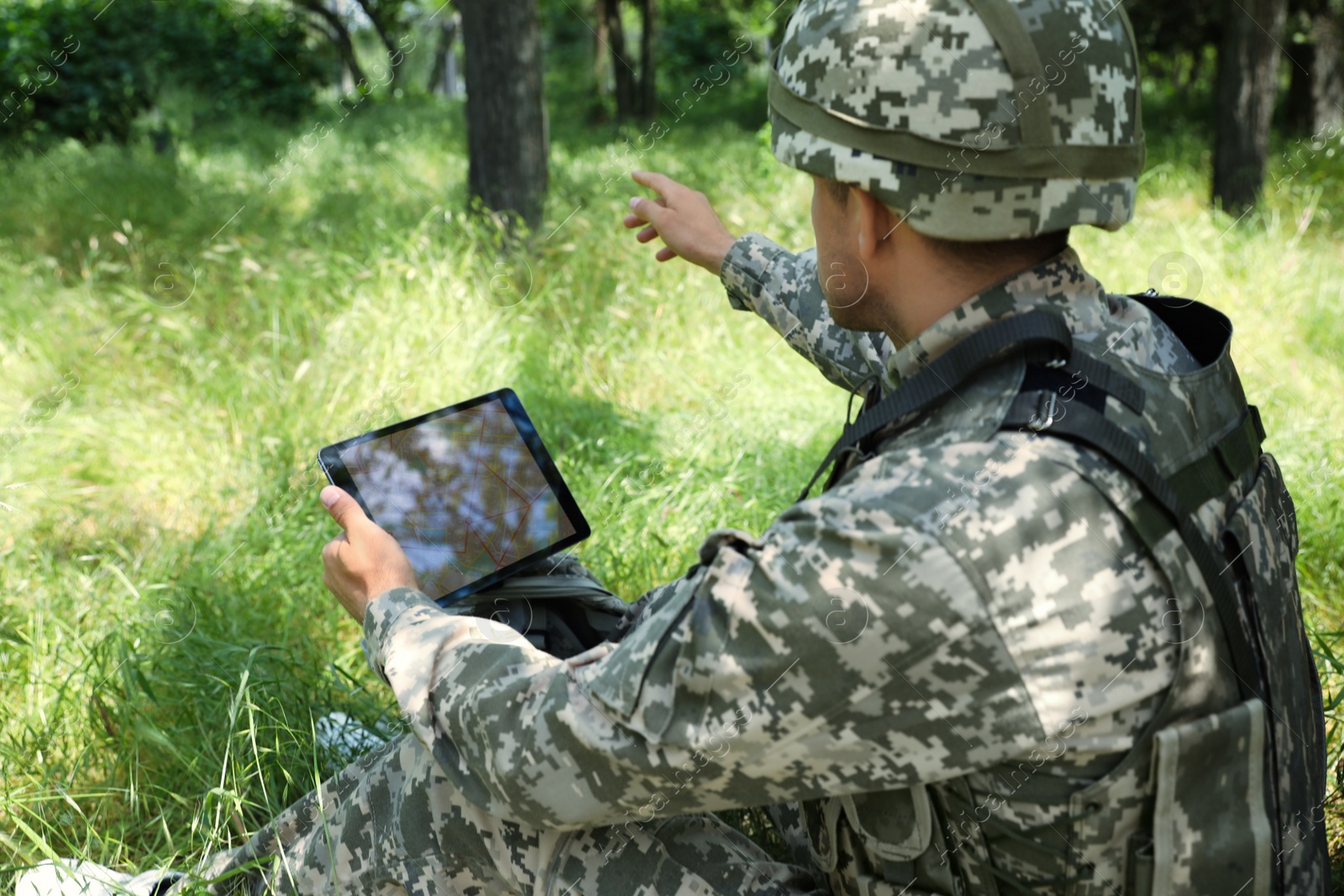 Photo of Soldier with backpack using tablet in forest