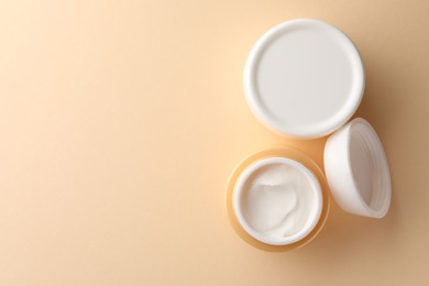 Photo of Jars of face cream on beige background, flat lay. Space for text