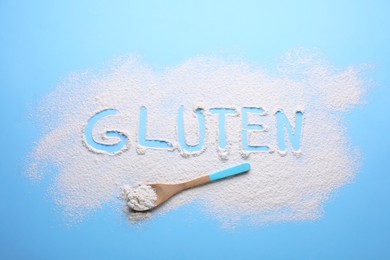 Photo of Spoon and word Gluten written with flour on light blue background, flat lay