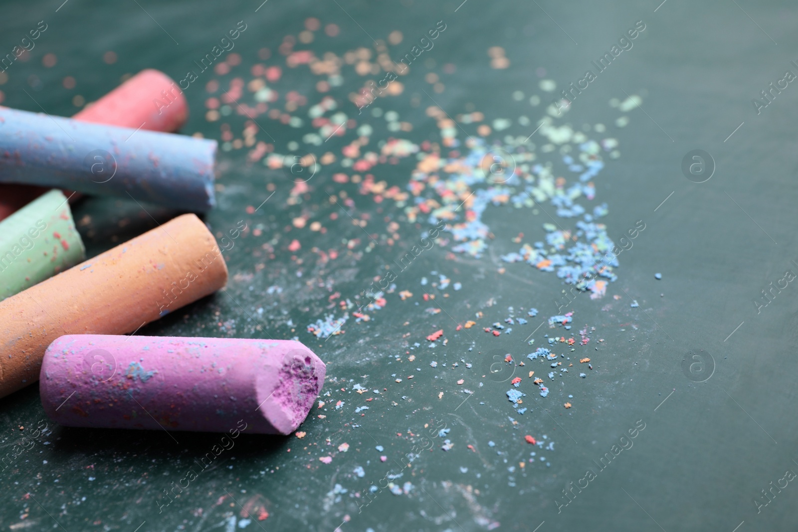 Photo of Pieces of color chalk on greenboard, closeup. Space for text