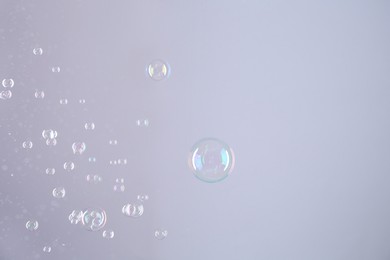 Beautiful transparent soap bubbles on grey background, space for text