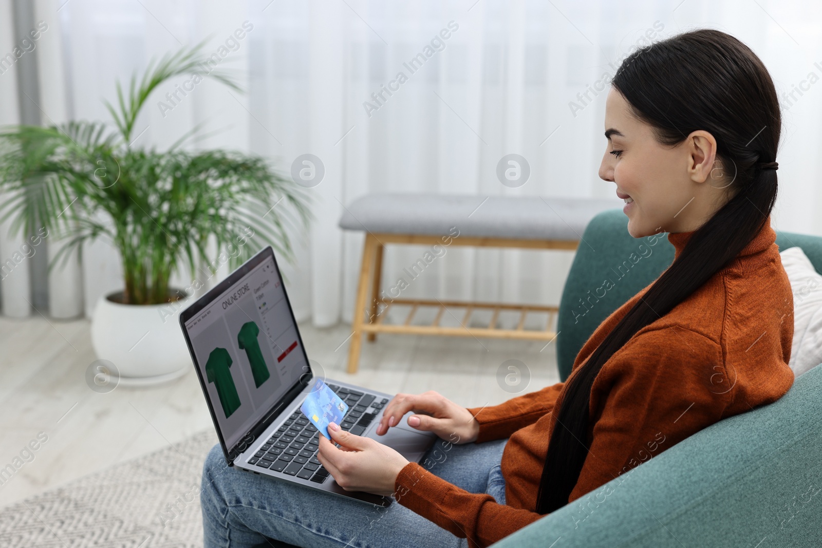 Photo of Beautiful young woman with laptop and credit card shopping online at home