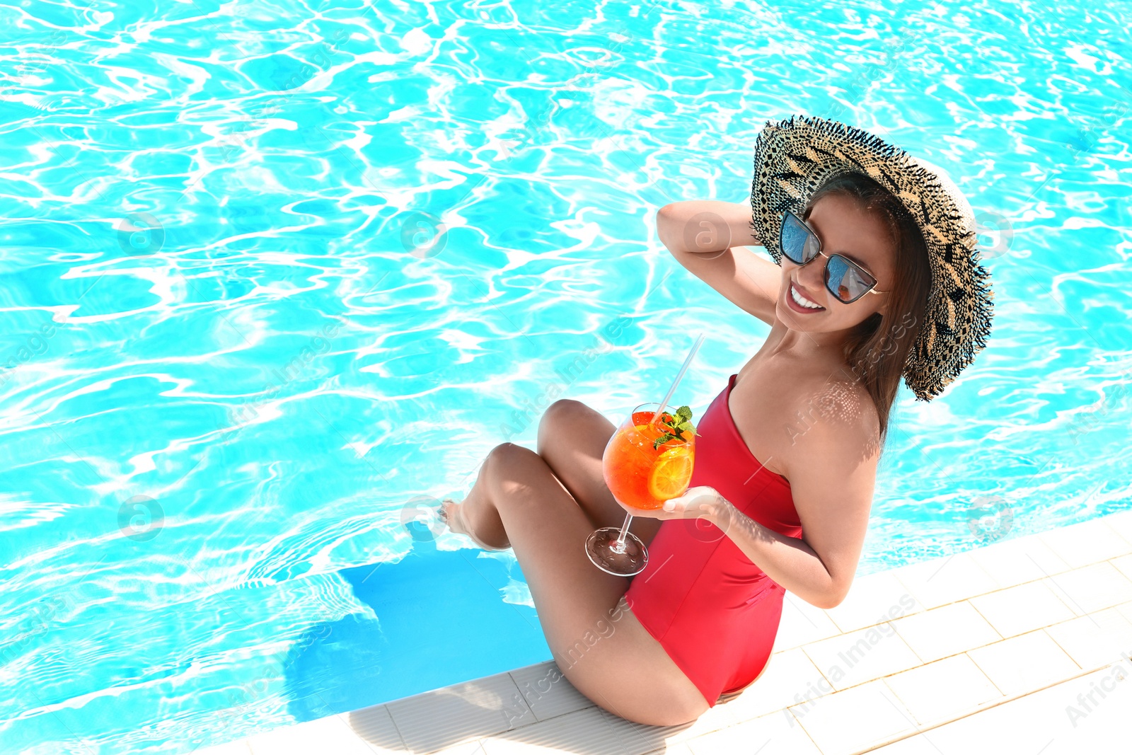 Photo of Woman with glass of refreshing drink near swimming pool. Space for text
