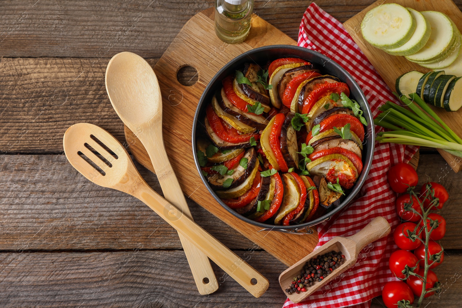 Photo of Delicious ratatouille, ingredients, spoon and spatula on wooden table, flat lay