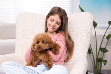 Photo of Little child with cute puppy in armchair at home. Lovely pet