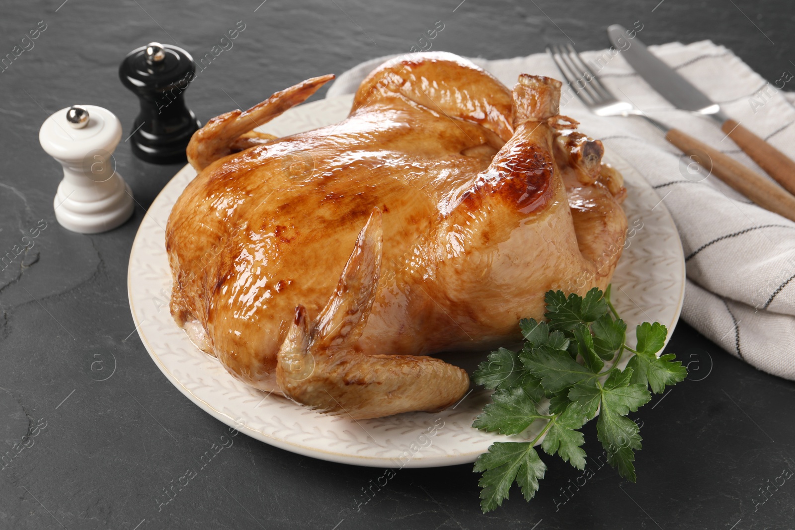 Photo of Tasty roasted chicken with parsley served on grey textured table