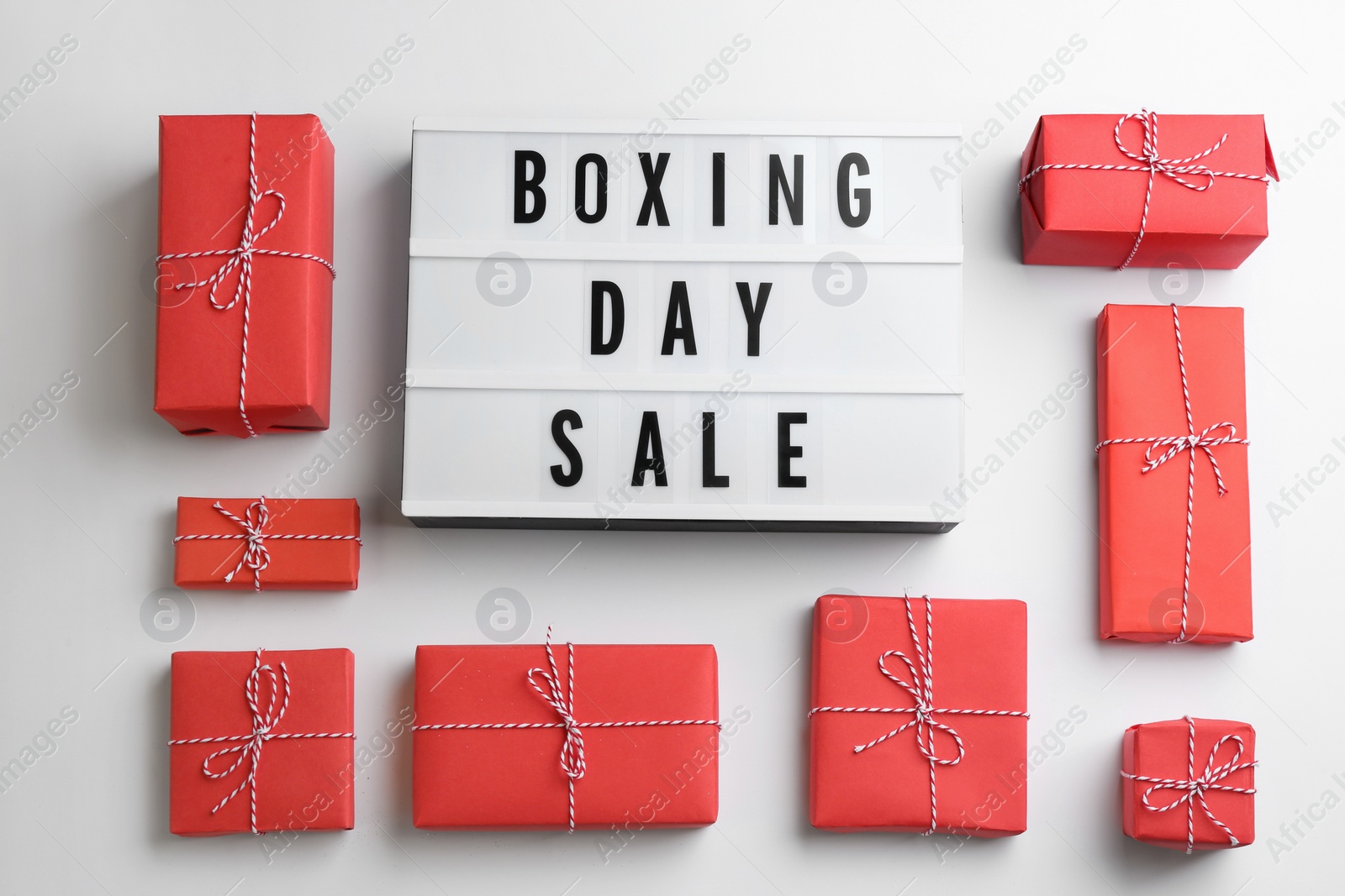 Photo of Lightbox with phrase BOXING DAY SALE and Christmas decorations on white background, flat lay