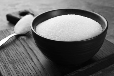 Granulated sugar in bowl on grey table, closeup