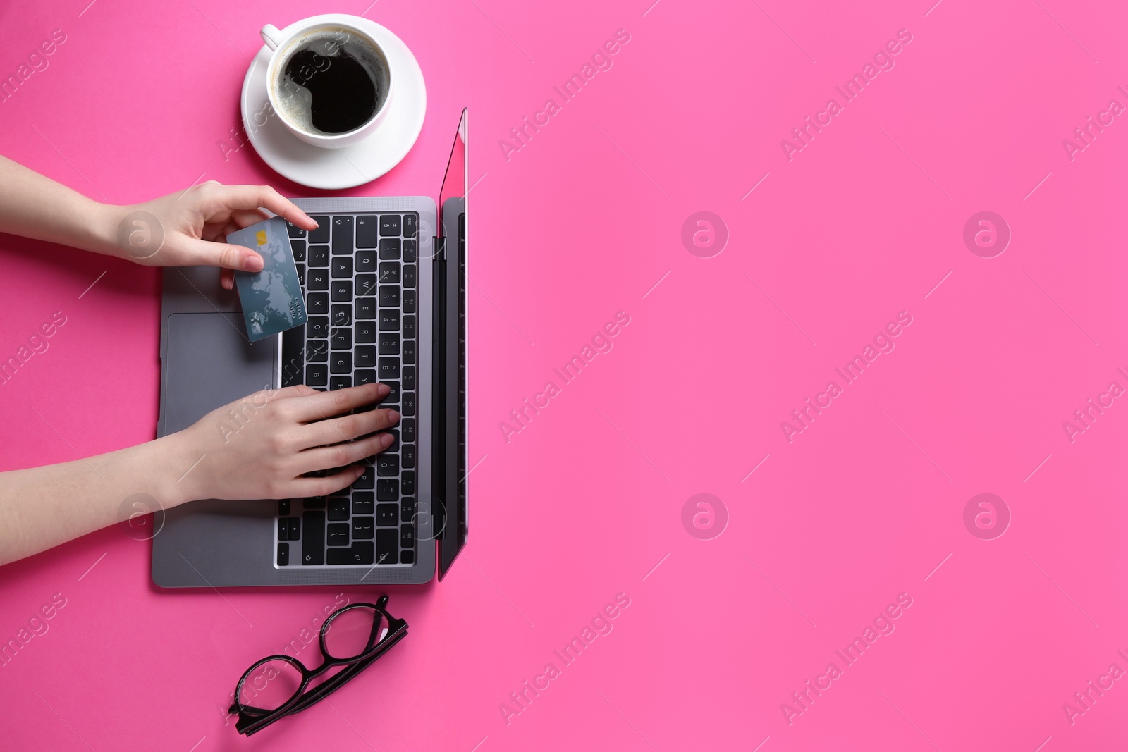 Photo of Online payment. Woman with laptop, credit card, glasses and coffee on pink background, top view. Space for text