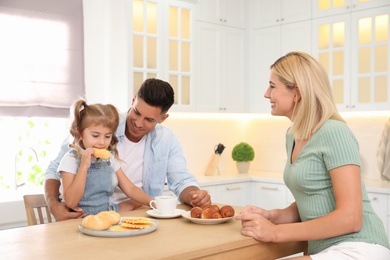 Photo of Happy family eating together at table in modern kitchen