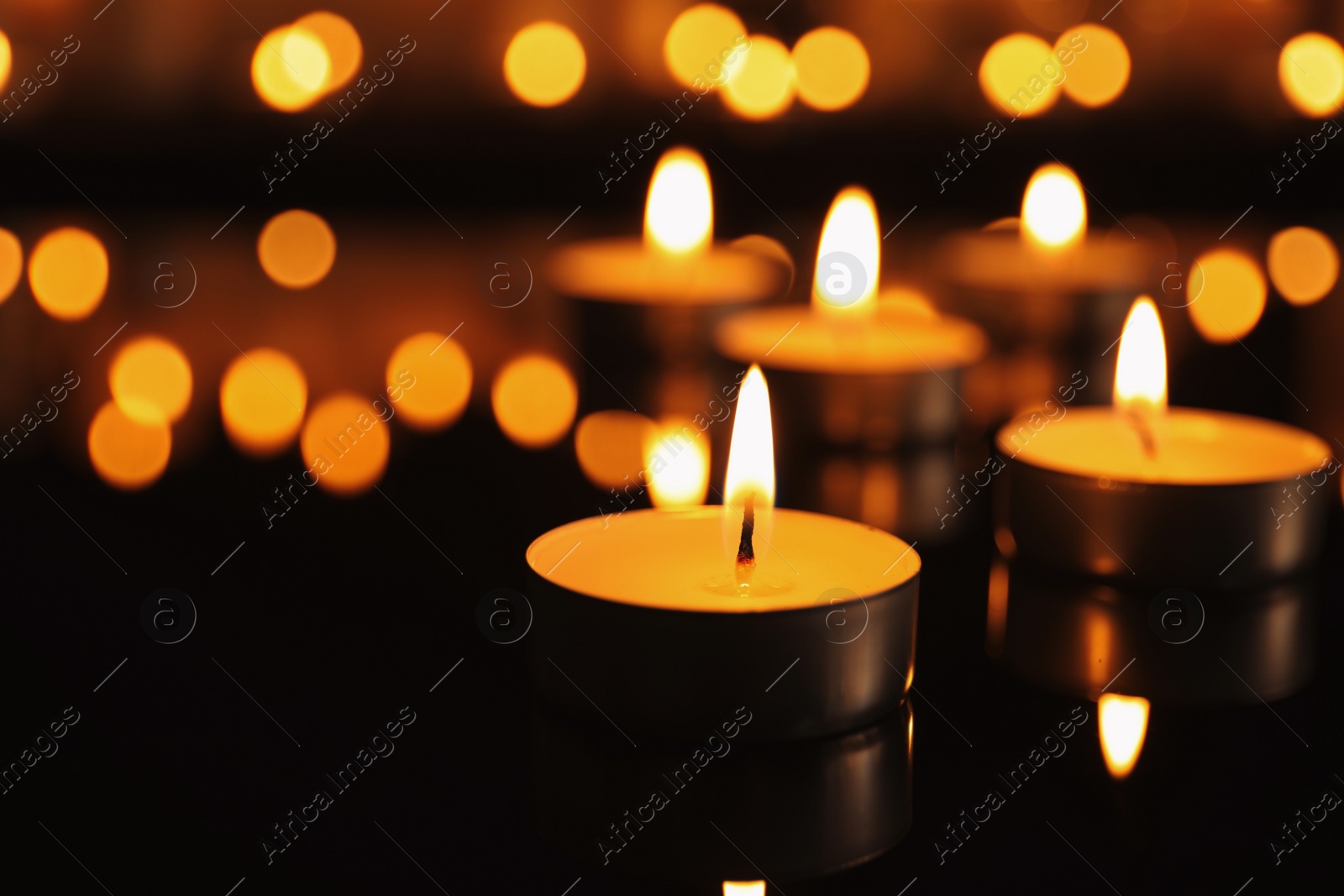 Photo of Burning candles on dark surface. Memory day