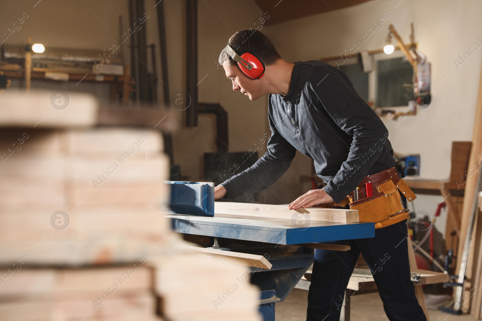 Photo of Professional carpenter working with surface planer in workshop