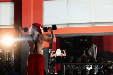 Young shirtless Santa Claus training in modern gym