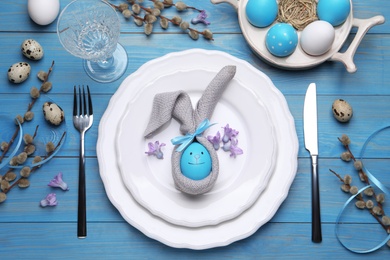 Festive Easter table setting with eggs on blue wooden background, flat lay