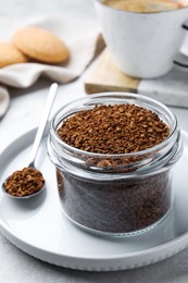 Photo of Spoon and glass jar with instant coffee on light table, closeup