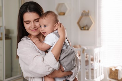 Photo of Happy young mother with her baby in nursery. Space for text