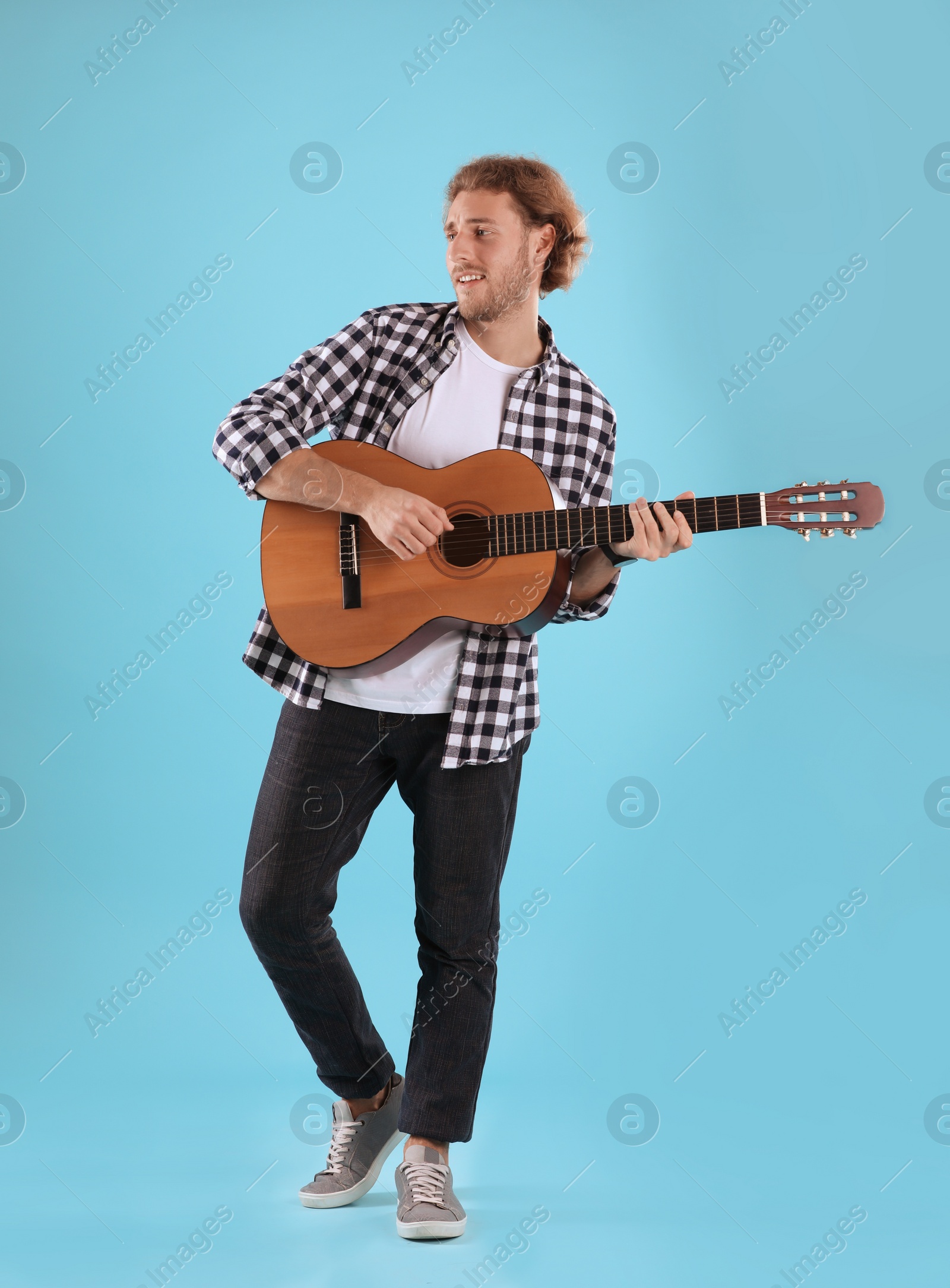 Photo of Young man playing acoustic guitar on color background