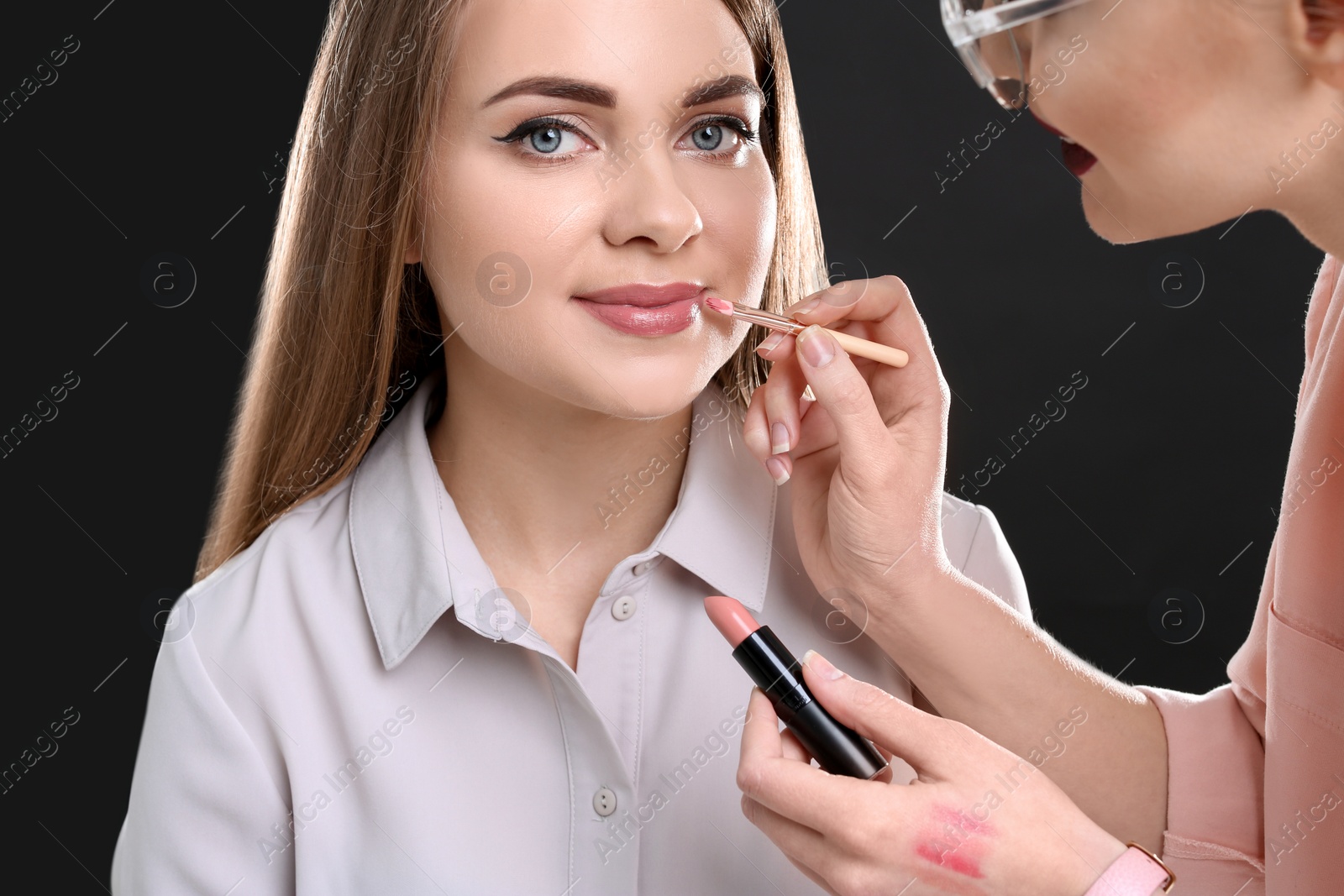 Photo of Professional makeup artist working with beautiful young woman in photo studio