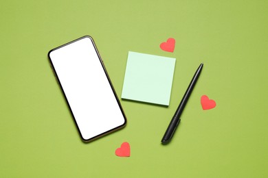 Long-distance relationship concept. Smartphone, empty note, paper hearts and pen on light green background, flat lay. Space for text