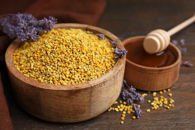 Photo of Fresh bee pollen granules, lavender, honey and dipper on wooden table, closeup