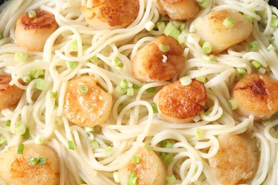 Photo of Delicious scallop pasta with green onion as background, closeup