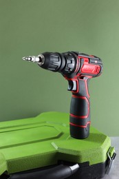 Photo of Electric screwdriver and case on table against pale green background