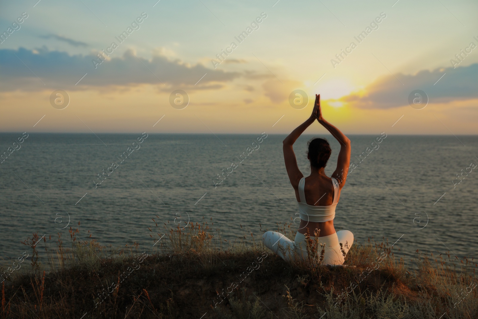 Photo of Woman meditating near sea, back view. Space for text