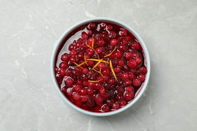 Photo of Fresh cranberry sauce with orange peel on light marble table, top view