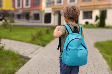 Photo of Little boy walking to kindergarten outdoors, back view. Space for text